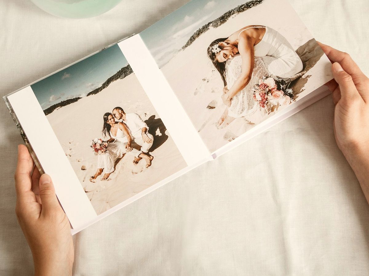 Twee handen houden een opengeslagen hardcover fotoboek vast